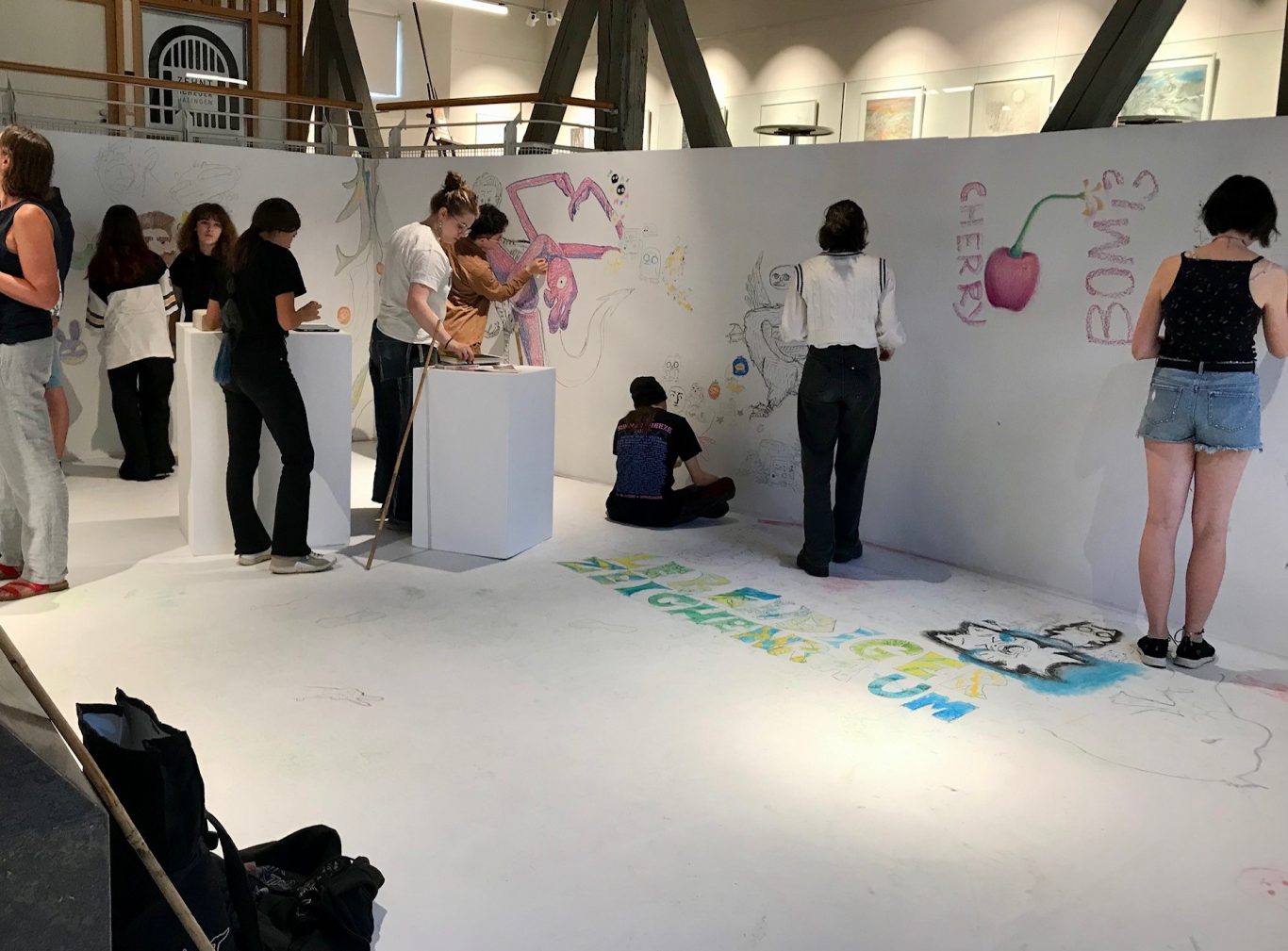 Gruppen von Menschen zeichnen an einer Wand in einem kreativen Raum.