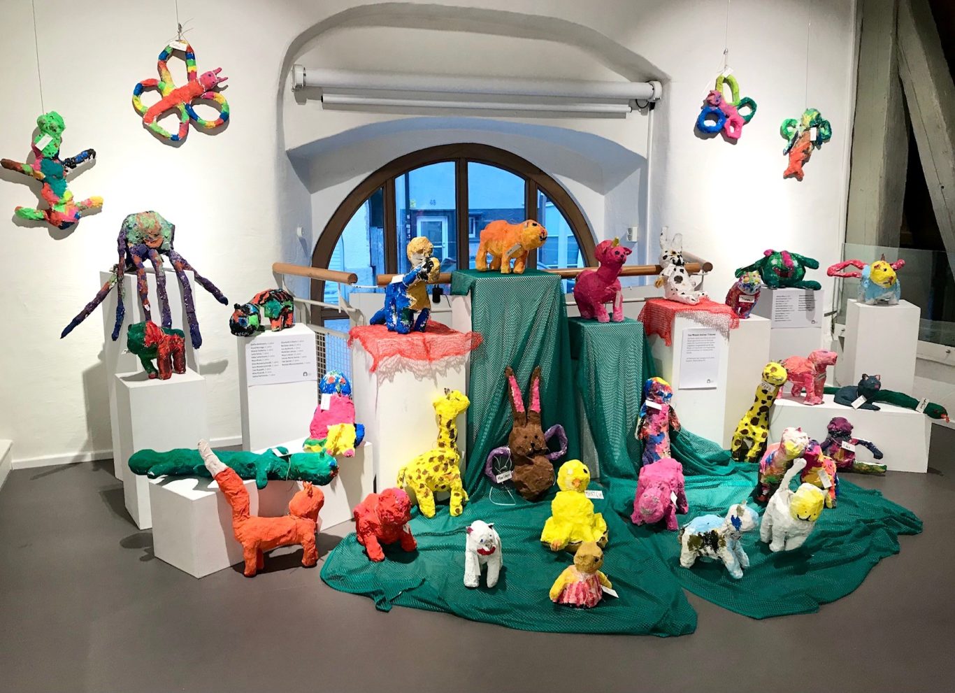Bunte, gestreifte Tierfiguren aus Kunststoffen in einem kreativen Ausstellungsraum.
