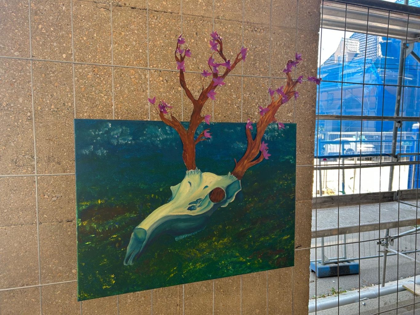 Ein Bild eines Schädels mit bunten, blühenden Ästen auf einem grünen Hintergrund.