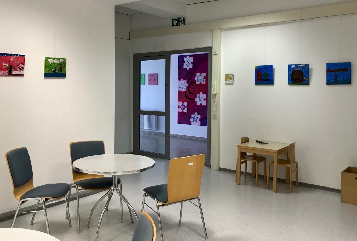 Heller Raum mit Tischen, Stühlen und Kunstwerken an der Wand.