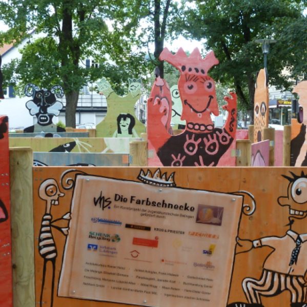 Bunte Figuren mit einem Informationsschild im Vordergrund.