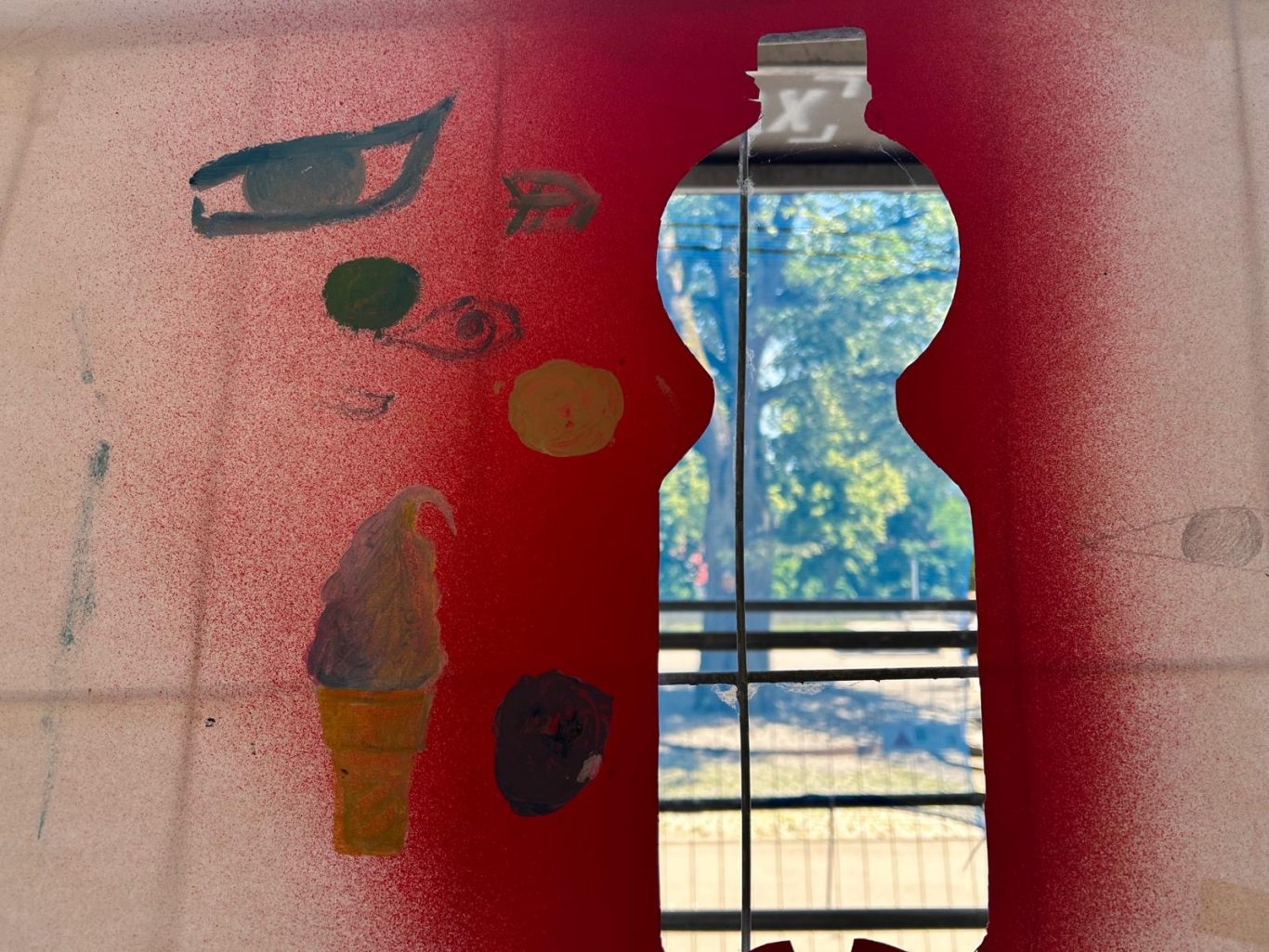 Blick durch eine Flasche mit bunten Farbspritzern und einem Waldblick im Hintergrund.