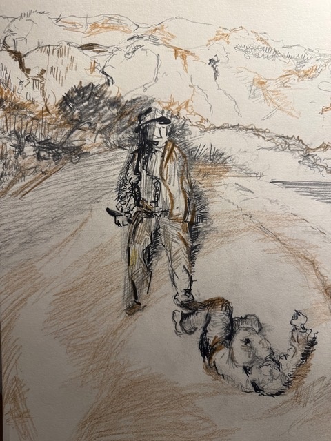 Ein Mann steht auf einem Weg, während ein anderer auf dem Boden liegt. Landschaft im Hintergrund.