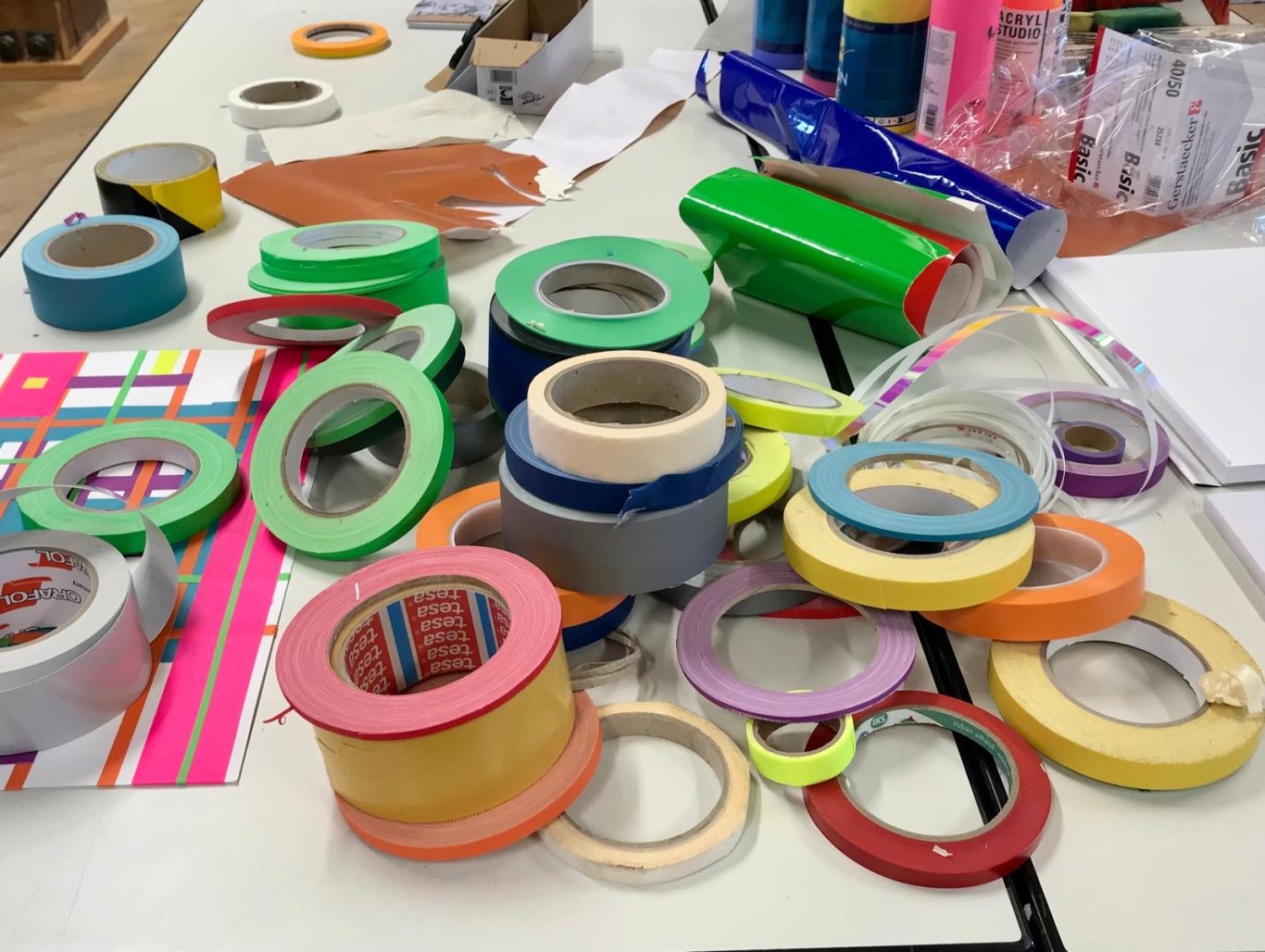 Bunte Klebebänder in verschiedenen Größen und Farben auf einem Tisch verstreut.