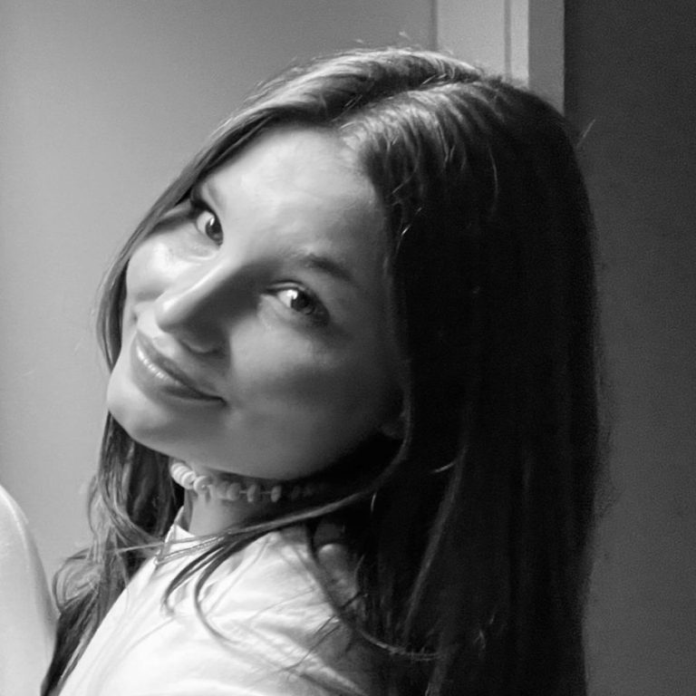 Junge Frau mit langen Haaren, lächelt und schaut über die Schulter.