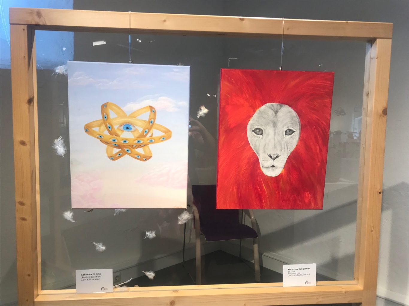 Zwei Kunstwerke: ein gelbes Atom-Symbol und ein roter Löwe mit grauem Gesicht.