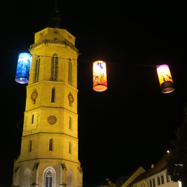 Beleuchtete, farbig gestaltete Laternen von einem Kirchturm.