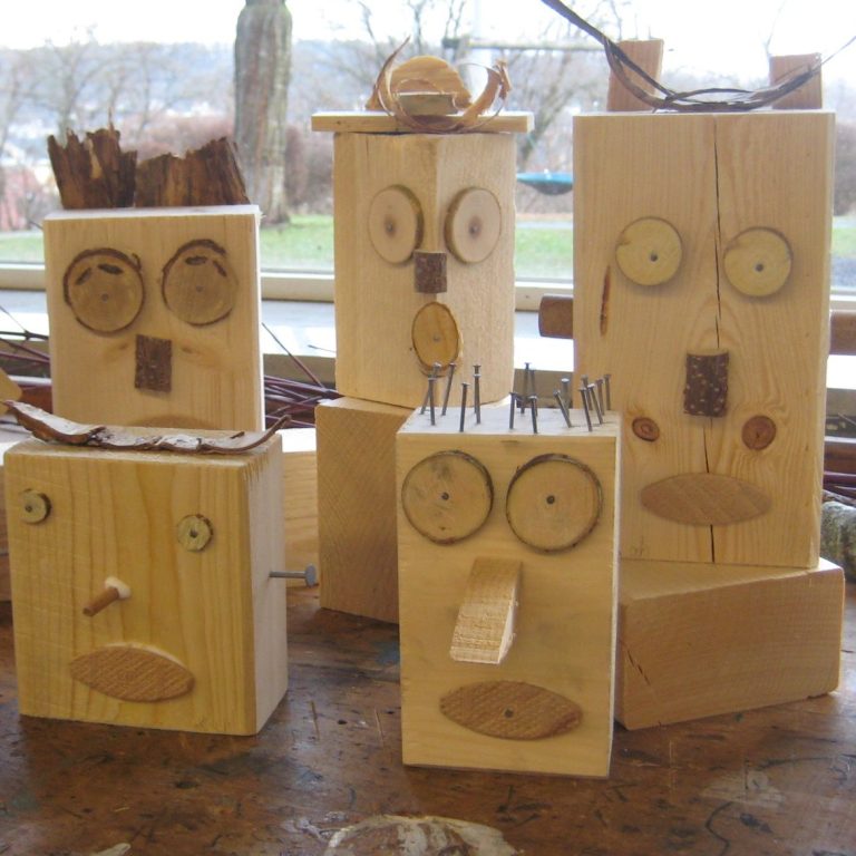 Fünf hölzerne Figuren mit verschiedenen Gesichtern und Merkmalen.