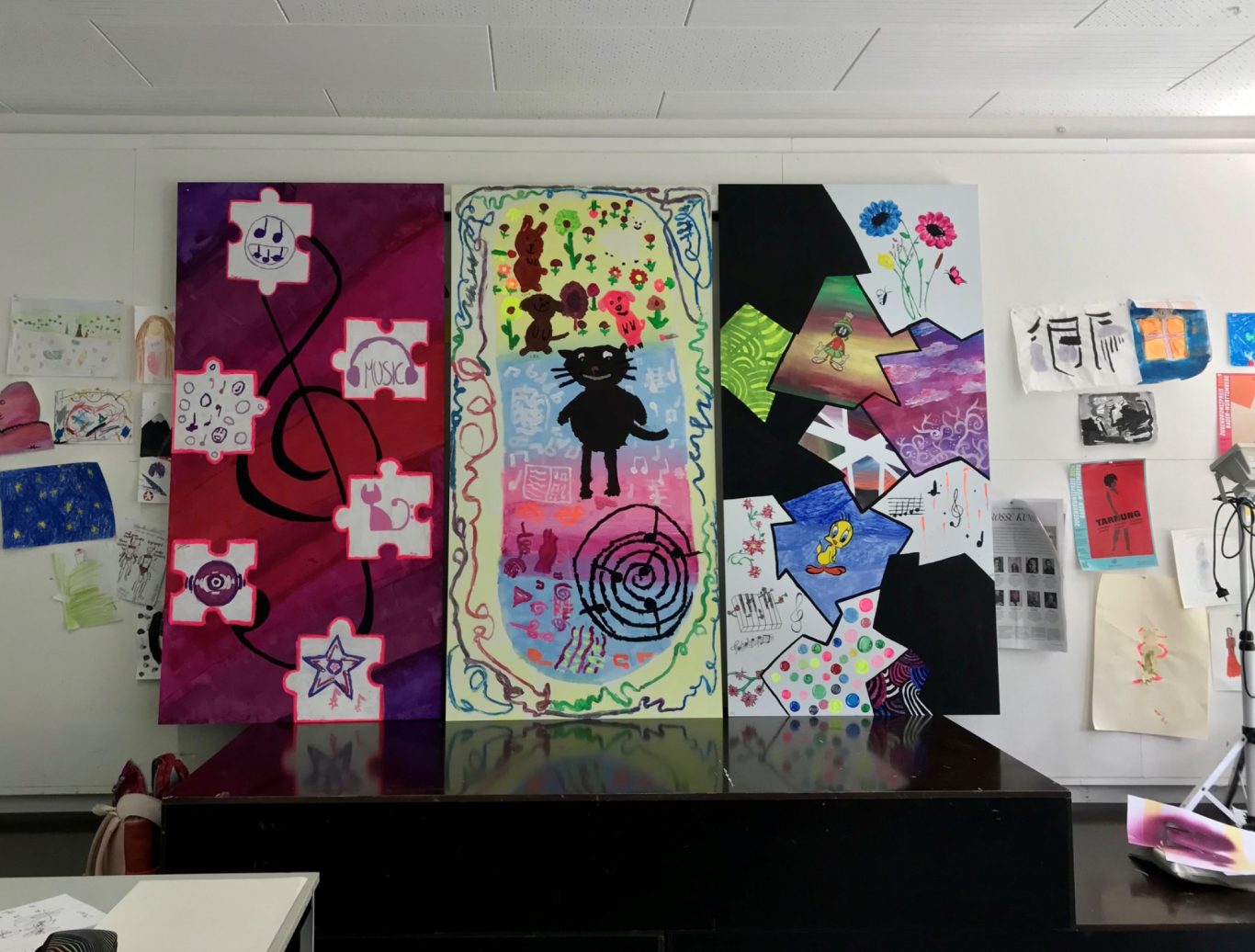 Bunte Wandgestaltung mit verschiedenen künstlerischen Arbeiten und Plakaten.